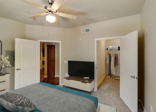 A bedroom with a bed, dresser, and a television. at Superstition Canyon Apartments, Mesa, Arizona