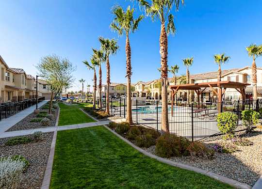 A sunny day at a residential area with palm trees and a pool.