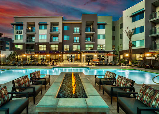 a swimming pool at night with an apartment building in the background at Elevation at the Village, Gilbert, 85295