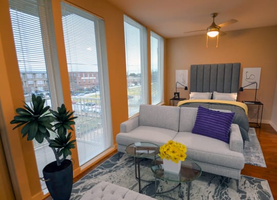a living room with a couch and a bed in a room with large windows at Link Apartments® Canvas, Atlanta, GA, 30312