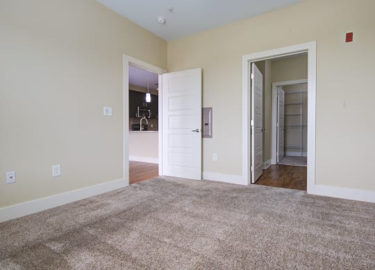 a bedroom with a carpeted floor and an open door  at Link Apartments® Brookstown, Winston Salem