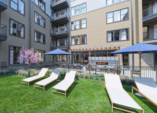 an outdoor lounge area with lounge chairs and umbrellas in front of an apartment building at Link Apartments NoDa 36th, Charlotte