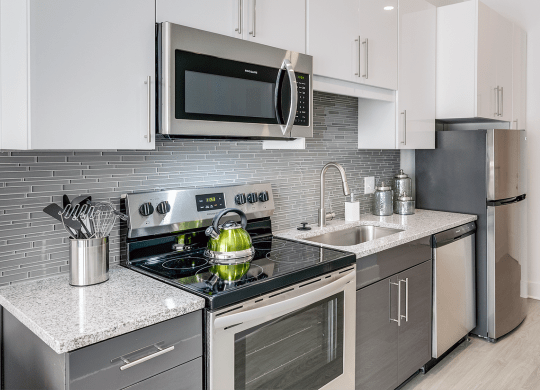 a kitchen with stainless steel appliances and white cabinets  at Link Apartments® Mixson, South Carolina