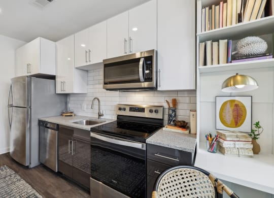 a kitchen with stainless steel appliances and white cabinets at Link Apartments® Broad Ave, Memphis, Tennessee