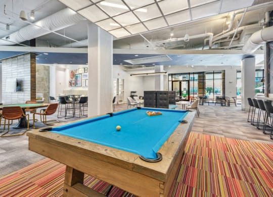 a pool table in a lobby with tables and chairs at Link Apartments Innovation Quarter, Winston Salem, NC