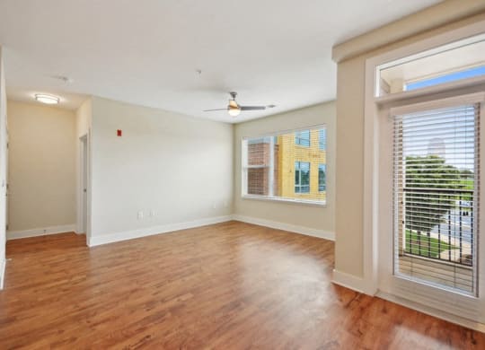 an empty living room with a large window and wood flooring at Link Apartments® Brookstown, Winston Salem, NC, 27101