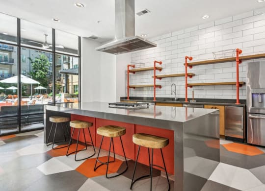 the kitchen has a large island with orange stools and stainless steel appliances at Link Apartments Innovation Quarter, Winston Salem, 27101