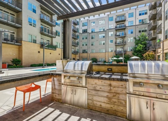 an outdoor kitchen with a grill and a pool in an apartment building at Link Apartments Innovation Quarter, Winston Salem, NC