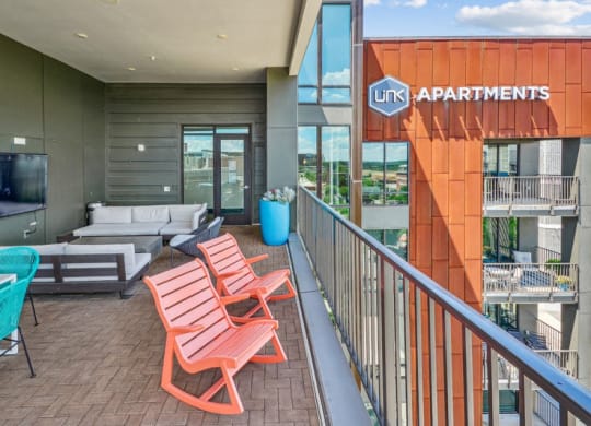 a balcony with a couch and chairs and a television at Link Apartments Innovation Quarter, Winston Salem, NC, 27101