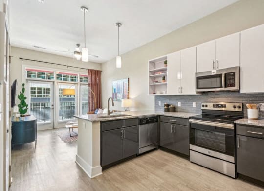 a large kitchen with stainless steel appliances and white cabinets at Link Apartments Innovation Quarter, Winston Salem