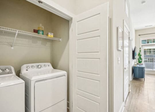 a laundry room with a washer and dryer and a white door at Link Apartments Innovation Quarter, Winston Salem