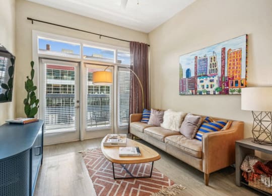 a living room with a couch and a tv and sliding glass doors at Link Apartments Innovation Quarter, North Carolina