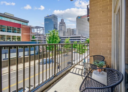 the view of the city from the balcony of a condo with a chair and table at Link Apartments Innovation Quarter, Winston Salem, NC, 27101