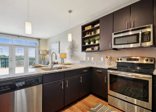 a modern kitchen with stainless steel appliances and granite counter tops at Link Apartments® Brookstown, Winston Salem, NC, 27101