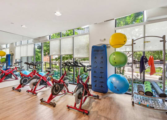 the gym has plenty of exercise equipment and floor to ceiling windows at Link Apartments Innovation Quarter, North Carolina