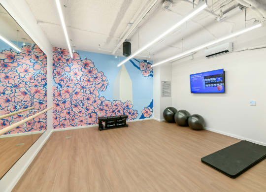 a yoga studio with a wooden floor and a wall with a screen and exercise balls  at Link Apartments® H Street, Washington, 20002
