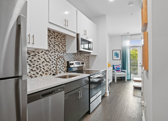 Studio kitchen with stainless steel appliances and quartz counters at Link Apartments® Mint Street in Uptown Charlotte, NC.
