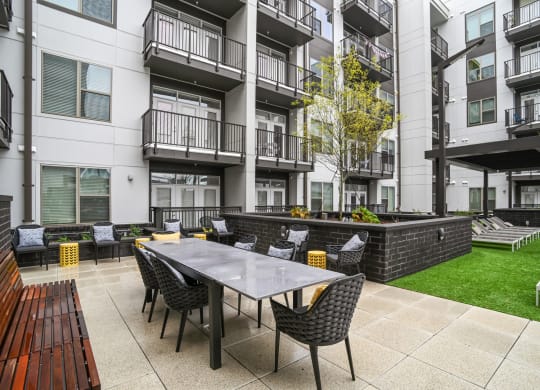 an outdoor patio with a table and chairs in front of an apartment building