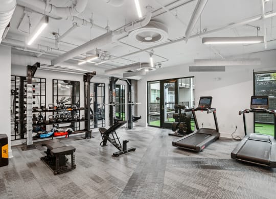 a workout room with treadmills and other equipment in a building with white walls