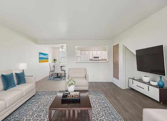 A living room with a white couch, a coffee table, and a television.