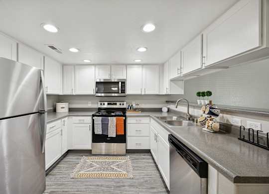A modern kitchen with a stainless steel refrigerator and white cabinets.