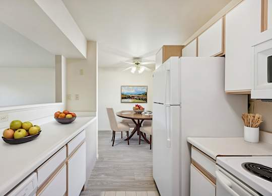 A kitchen with white appliances and a table with chairs.