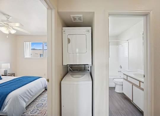 A bedroom with a bed, a washing machine, and a bathroom.