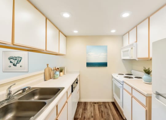 a kitchen with white appliances and wooden cabinets and a sink