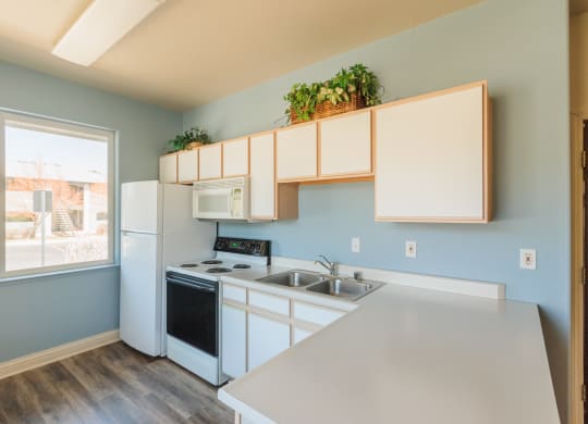 an empty kitchen with white appliances and a large window