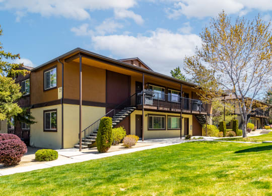 the front of a house with a green lawn and a staircase
