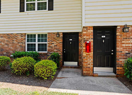 A house with two black doors and a red fire hydrant.