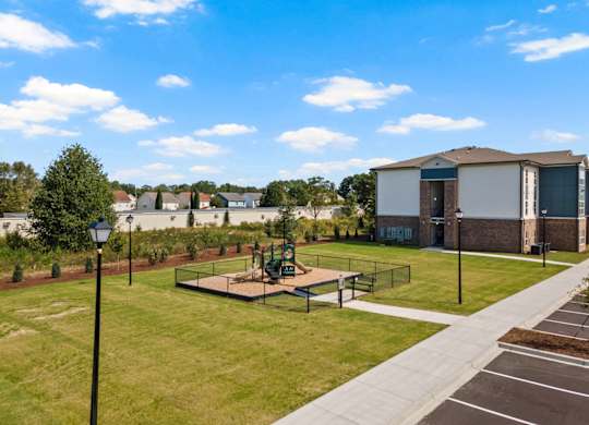 A park with a playground and a building in the background.