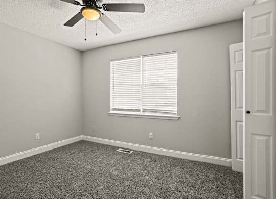 A room with a ceiling fan and a window with blinds.