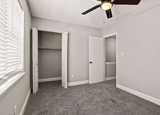 A room with a ceiling fan and carpeted floor.