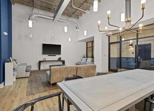 Aug Smith on Main community room with three couches, a TV, a dining room table and glass doors.
