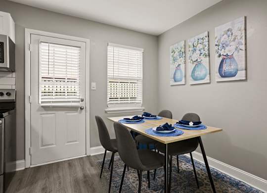 A dining room with a table set for two and two vases on the wall.