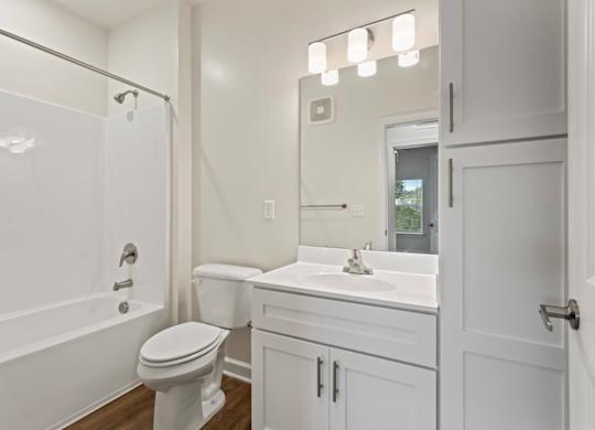 A white bathroom with a toilet, sink, and mirror.