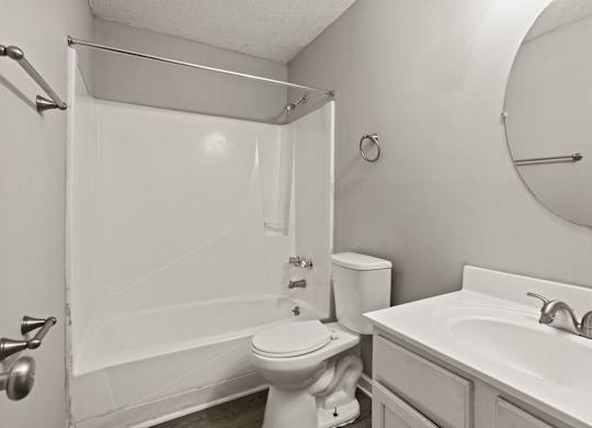 A white bathroom with a toilet, sink, and shower.