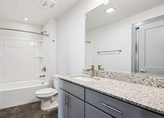 Bathroom in Converse Mill Lofts in Spartanburg, SC with granite countertops and tub/shower