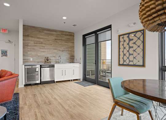 Aug Smith on Main staged unit with furniture, table, couches, carpet, kitchen, and a balcony.