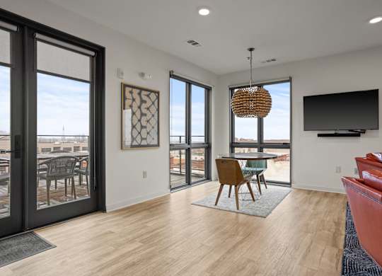 Aug Smith on Main staged modern living room on upper floor with balcony. The unit features leather chairs, carpet and a TV.