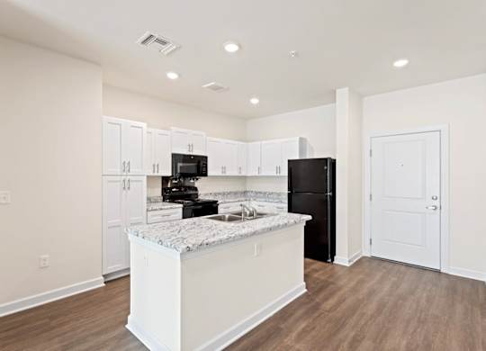 Peaks of Lexington Apartments Kitchen with Black Appliances, Granite Countertops and White Cabinetry and connected living room
