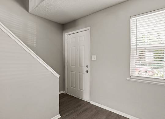 A white door is in a room with a window.