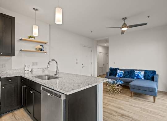 Connected kitchen and living room at Aug Smith on Main. The kitchen features stainless steel appliances and granite countertops.