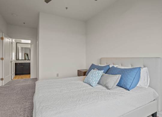 Aug Smith on Main staged bedroom with large bed and headboard and connected bathroom