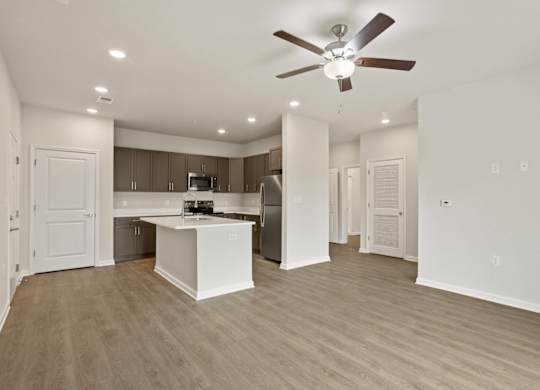 A spacious kitchen and living room with a ceiling fan.