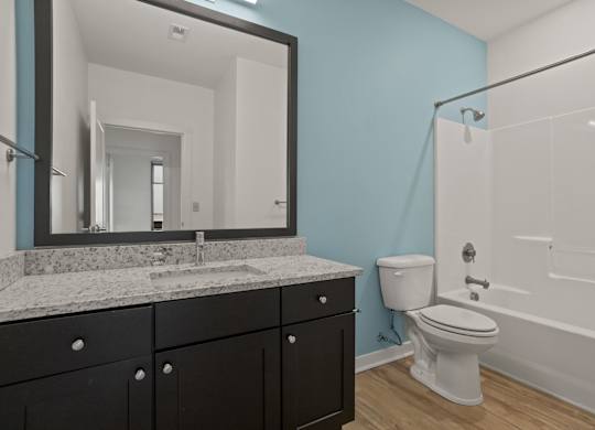 Bathroom with blue walls, a toilet, a bathtub/shower and granite countertops at Aug Smith on Main