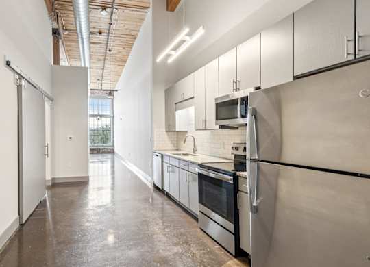 Kitchen and hallway at Converse Mill Lofts in Spartanburg, SC with stone floor and stainless steel appliances