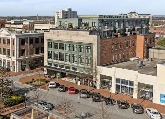 Overhead view of exterior of Aug Smith on Main, apartments in downtown Spartanburg. The building is a renovated factory in the middle of other stores on the strip.