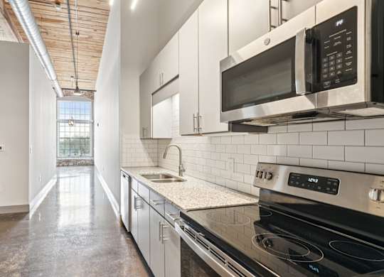 Kitchen and hallway at Converse Mill Lofts in Spartanburg, SC with stone floor and stainless steel appliances